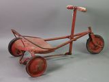 an old red tricycle with wheels and a wooden seat