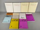 six livres posés sur une table, sur fond blanc, avec des couvertures jaunes et roses