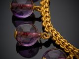 a close up of a necklace with purple beads on a black surface