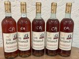 cinq bouteilles de vin sont alignées sur une table en bois