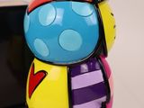 brightly colored figurine sitting next to a cell phone on a white surface