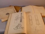 trois livres ouverts posés sur une table, sur lesquels figurent des dessins