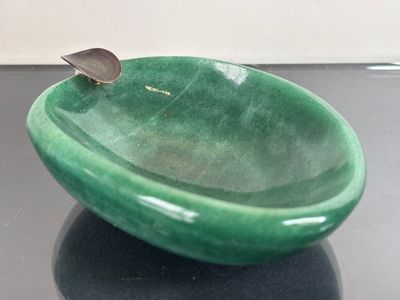 a green bowl with a spoon in it sitting on a table