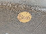 a close up of a brown leather bag with a brown logo on it