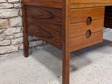 an image of a wooden desk with drawers in front of a stone wall