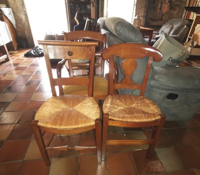 two wooden chairs sitting next to each other on a tiled floor