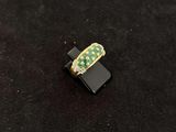 a green and gold ring sitting on top of a black surface