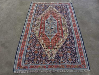un tapis oriental posé au sol, orné d'un motif bleu et rouge