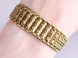 gold plated bracelet on a woman ' s wrist with a diamond clasp