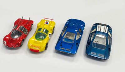 quatre petites voitures sont alignées sur une surface blanche