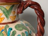 a vase with a handle that has a flower design on it