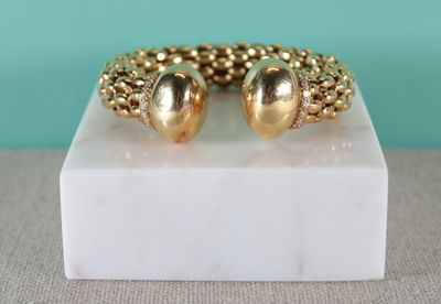 un gros plan d'un bracelet en or posé sur un bloc de marbre