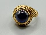 une image d'une bague en or avec une pierre bleue au centre