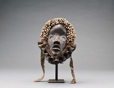 une image représentant un masque en bois posé sur un socle, sur fond gris