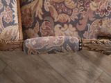 a close up of the arm of a chair with a floral upholstered back