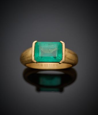 gros plan d'une bague en or avec une pierre en émeraude