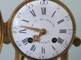 a gold clock with roman numerals on the face of it
