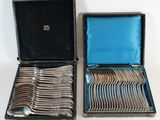 two open cases with silverware in them on a white surface