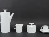three cups and a teapot sitting on a table