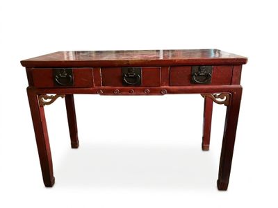 une image représentant une table rouge à trois tiroirs, avec un plateau en marbre