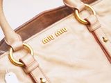 a tan purse with a tag on the handle
