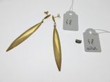 deux paires de boucles d'oreilles en or, avec leurs étiquettes, posées sur un fond blanc