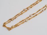 a close up of a gold chain with pearls on it