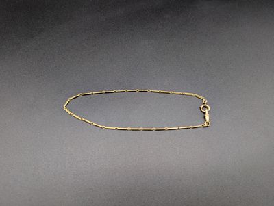 un bracelet en chaîne d'or muni d'un fermoir, sur fond gris