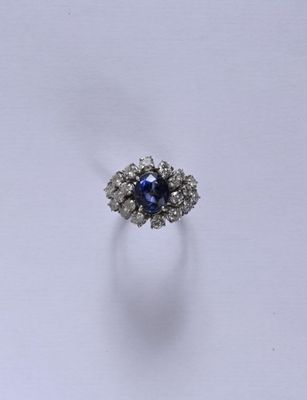 gros plan d'une bague avec une pierre bleue entourée de diamants blancs
