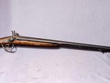 Un vieux fusil repose sur un drap blanc, avec une crosse en bois.