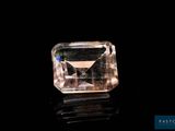 a pink diamond on a black surface with a black background