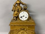 a gold clock with a woman holding a bird on top of it