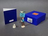 une petite figurine représentant un homme tenant une pancarte à côté d'une boîte