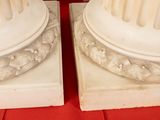 two white marble columns on a red table