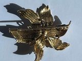 une broche en forme de fleur dorée sur un fond blanc