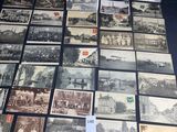 Plusieurs vieilles cartes postales sont disposées sur une table, ornées d'un ruban blanc