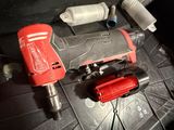 a red drill and two other tools sitting on a table