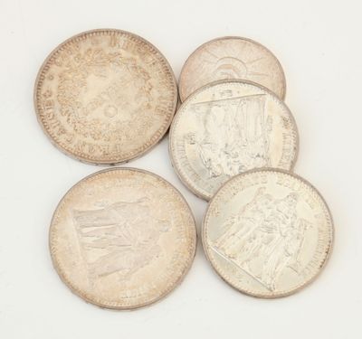 six types différents de pièces d'argent sur une surface blanche