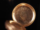 a close up of a gold pocket watch with a black background