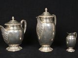 three silver vases sitting next to each other on a black background