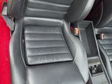 the interior of a car with red carpet and black leather seats
