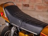 a yellow motorcycle with a black seat sitting in front of a brick wall