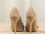 pair of beige sued high heeled shoes on a wooden surface