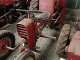 several old tractors are parked in a row in a garage