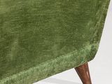 the back of a green velvet chair with wooden legs