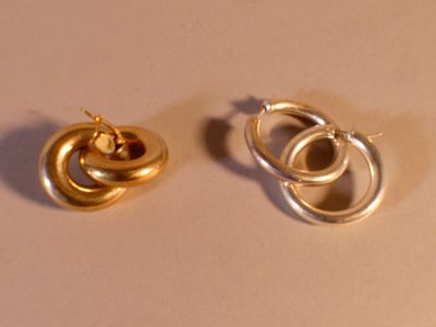 deux paires de boucles d'oreilles en or posées sur un fond blanc