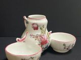 three pieces of porcelain pottery sitting on top of a black surface