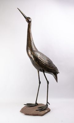 statue en bronze représentant un oiseau perché sur un rocher, sur fond blanc