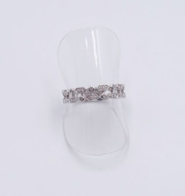 un gros plan d'une bague posée sur un présentoir transparent, sur une surface blanche