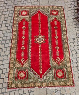 un tapis rouge posé sur un sol pavé, orné d'une croix